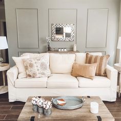 a living room filled with furniture and pillows on top of a wooden table in front of a mirror