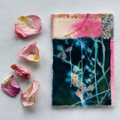 some pink and blue flowers are on a white surface next to a piece of paper