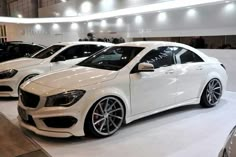 three white mercedes cla class cars on display at an auto show in the city