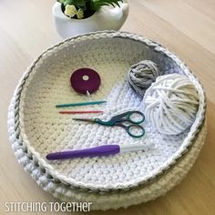 a crochet tray with yarn, scissors and balls of yarn on it next to a potted plant