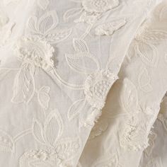 an image of white fabric with flowers and leaves on the bottom half, close up