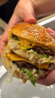 a hand holding a cheeseburger with lettuce and tomato