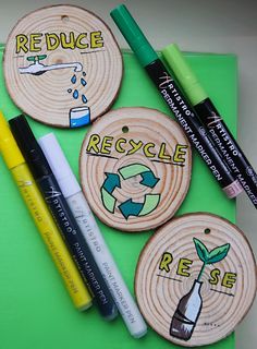 three wood burned coasters with markers and pens on them, including one that says reduce recycle