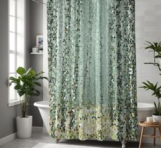 a bathroom with a green shower curtain next to a bathtub and potted plant