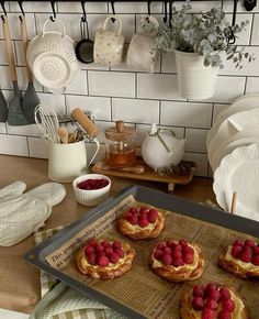 raspberries on top of puff pastry sitting on a tray in front of pots and pans