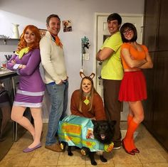 a group of people in costumes posing for a photo with a dog on the floor