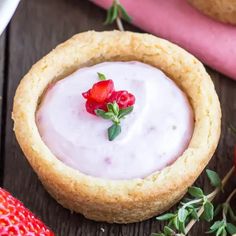 two strawberry shortcakes with whipped cream and strawberries next to them on a wooden table