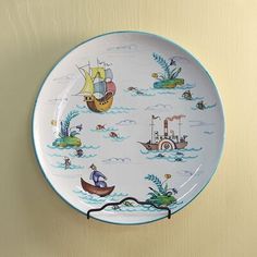 a blue and white plate with boats on it hanging from the wall next to a hook