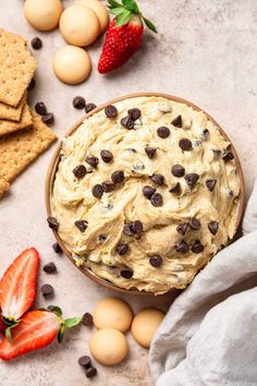 a bowl filled with peanut butter and chocolate chip cookies next to strawberries, eggs, and crackers