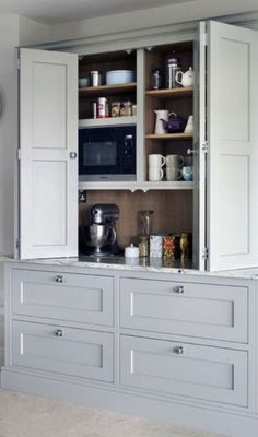 an open cabinet in the middle of a kitchen with lots of cupboards and drawers