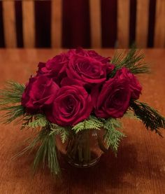 a vase filled with red roses on top of a wooden table