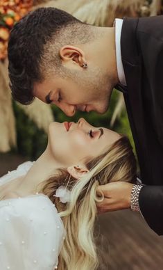 a bride and groom kissing each other outside