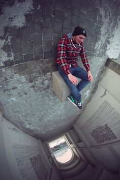 a man is sitting on the edge of a wall with his feet up in the air