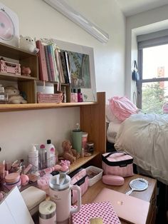 a cluttered dorm room with pink accessories on the desk and bed in the background