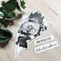 two stickers with trees and compass on them next to a potted green plant