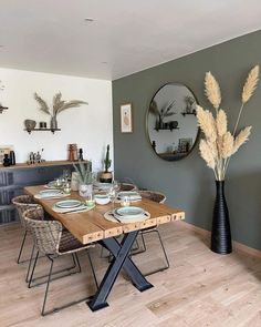 a dining room table with plates and bowls on it, in front of a mirror