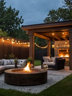 a fire pit in the middle of a backyard with lights strung around it and patio furniture