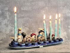 a group of candles sitting on top of a blue plate with houses and cats in it