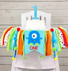 a one year old birthday cake on a chair with the number one banner over it