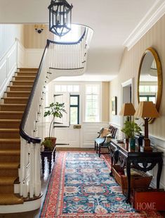 a hallway with stairs and rugs on the floor in front of a lamp fixture