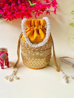 Elevate your accessory game with the Byra Sequence Potli Bag for women, a luxurious blend of elegance and contemporary style. This exquisite potli bag is designed to make a statement, perfect for adding a touch of glamour to any outfit. Crafted from high-quality Silk, the bag is adorned with intricate sequence work that shimmers beautifully with every movement. The soft, plush Silk provides a rich texture, while the delicate sequences add a layer of opulence and sparkle, making this bag a true standout piece. The Byra Sequence Potli Bag features a convenient drawstring closure, ensuring your essentials are secure while offering easy access. The elegant handle allows for comfortable carrying, whether you choose to wear it on your wrist or hold it in your hand. Perfect for weddings, festive Gold Potli Bag With Latkans For Reception, Festival Potli Bag With Latkans For Reception, Festival Reception Potli Bag With Latkans, Festive Potli Bag With Latkans For Receptions, Traditional Bags With Latkans For Reception, Festival Potli Bag With Gold Embroidery For Receptions, Gold Embroidered Potli Bag For Receptions And Festivals, Gold Potli Bag With Gota Work For Reception, Festive Potli Bag With Gold Embroidery For Reception