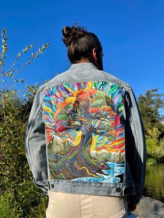 a woman wearing a jean jacket with an image of a tree on it