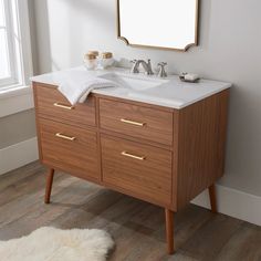 a bathroom vanity with a mirror above it and a rug on the floor next to it