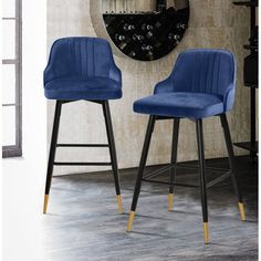 two blue velvet bar stools in front of a wall with a clock on it