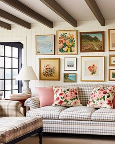 a living room filled with furniture and lots of framed pictures on the wall above it