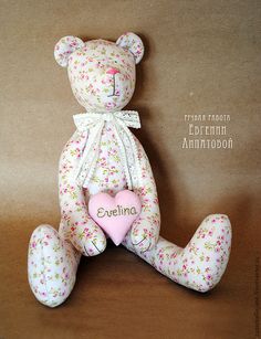 a teddy bear holding a pink heart sitting on top of a wooden table next to a brown wall