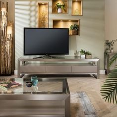 a living room with a large flat screen tv on top of a glass coffee table