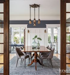 the dining room table is surrounded by gray chairs and an area rug that matches the blue walls