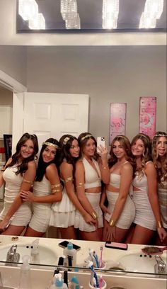 a group of beautiful women standing in front of a bathroom mirror posing for a photo