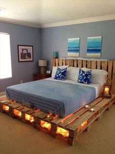 a bed made out of wooden pallets with candles on each side and two pictures above it