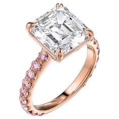 a rose gold ring with a princess cut diamond and pink sapphire stones on the band