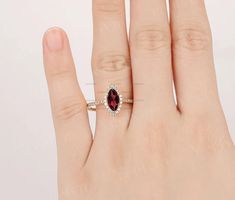 a woman's hand with a ring on it that has a red stone in the middle