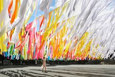 there are many colorful streamers flying in the air over a person walking on the street