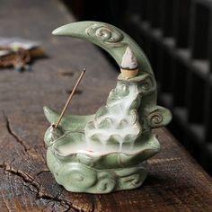 a green ceramic statue sitting on top of a wooden table next to a pen holder