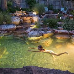 a woman swimming in a pool surrounded by rocks