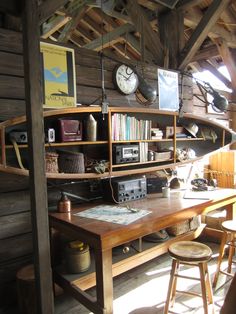 a wooden desk sitting under a roof with bookshelves and clocks on top of it