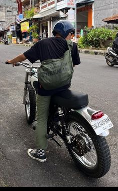 a man riding on the back of a motorcycle down a street