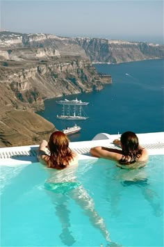 two women sitting in a pool overlooking the ocean