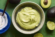 an avocado dip in a bowl next to sliced limes and other fruit