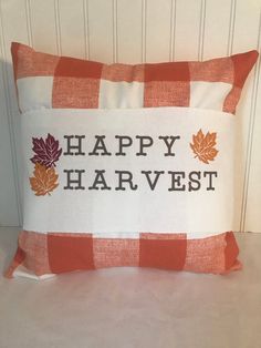 a happy harvest pillow sitting on top of a white table next to a wooden wall