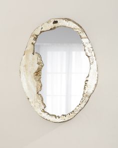 a mirror that is on the wall in front of a white wall with curtains behind it