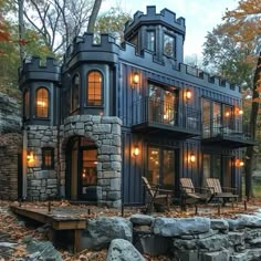 a house made out of shipping containers in the woods with lots of trees and rocks