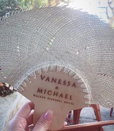 a person holding up a wooden sign that says vanessa and michael with an umbrella in the background