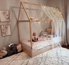 a baby sitting on a bed in a room with lights strung from the ceiling and curtains