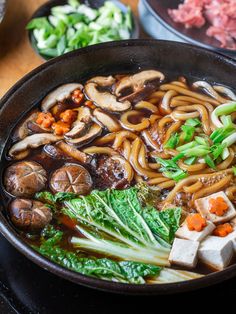 a bowl of noodles with mushrooms, carrots and broccoli on the side