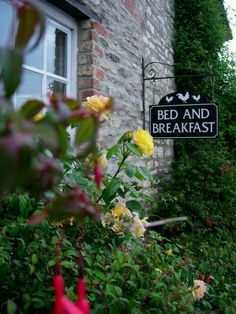 a bed and breakfast sign in front of some flowers